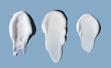 Mavi arka planda krem rengi kozmetik darbeler. Cilt bakımı.