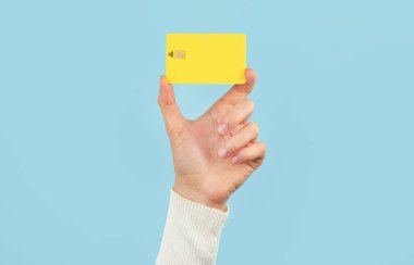 Mavi arka planda ödeme kartı tutan bir kadın. Banka kartı düzeni.