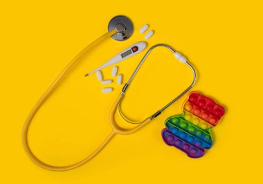 Pediatri konsepti. Sarı steteskop ve sarı arka planda oyuncaklar. Çocuk ilaçları işte. Tıbbi geçmiş.