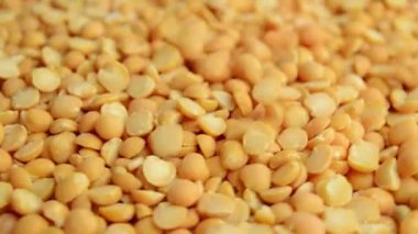 Yuvarlak, sarı bir bezelye düşer ve döner. Çiğ bezelye. Yan görünüm.