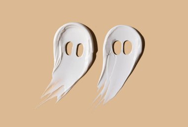 Halloween concept, ghosts in the form of cosmetic smears on a beige background. Moisturizing the skin in autumn. Autumn concept.