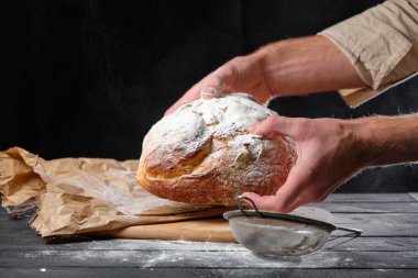 Adamın elinde taze bir somun ekmek var.