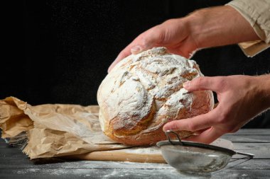Adamın elinde taze bir somun ekmek var.