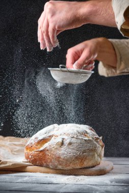 Fırıncı taze ekmeğe un serper.