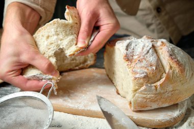 Elinde taze kesilmiş ekmek dilimleri tutan bir adam.