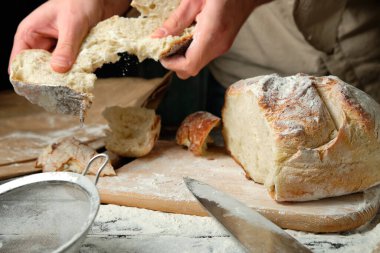 Elinde taze kesilmiş ekmek dilimleri tutan bir adam.