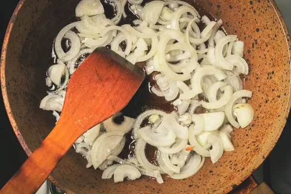 The process of frying onions in a pan