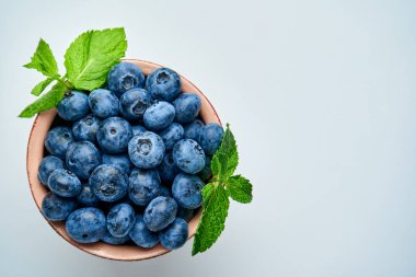 Hafif arka planda seramik bir kasede yaban mersini. Yukarıdan görüntüle