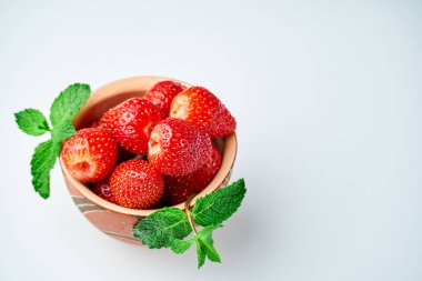 Hafif arka planda seramik bir kasede çilekler