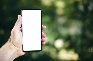 Elinde beyaz ekran olan akıllı telefon yeşil arkaplanda bulanık arkaplan ve yanında kopya alanı.