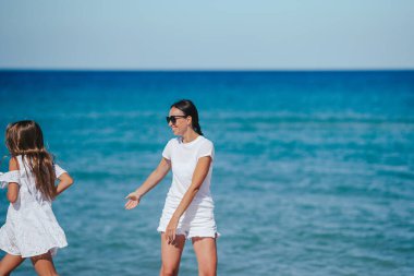 Genç, güzel anne ve sevimli küçük kızı tropikal sahilde eğleniyor.