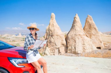 Happy woman with map on car vacation in mountains. Travel by car