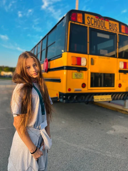 Beautiful teen girl getting on school bus. High quality photo