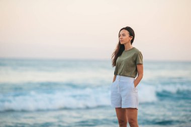 Genç ve güzel bir kadın, beyaz kumsalda dinleniyor.