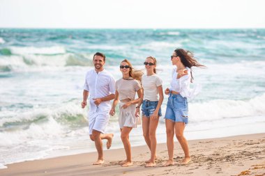 İki çocuklu ebeveynler kumsalda eğleniyor.