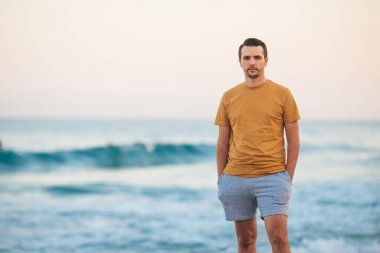 Young man on the beach look at the sea at sunset