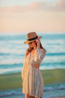 Young happy woman on the beach with soft sunset light