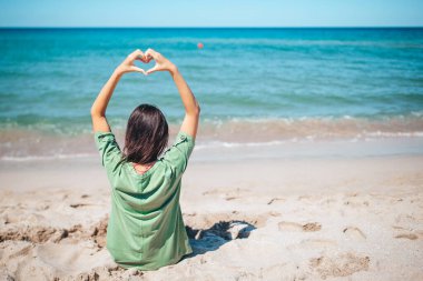 Genç ve güzel bir kadın, beyaz kumsalda dinleniyor.