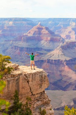 Dik bir yamaçta duran genç yürüyüşçü, yazın güneşli bir günde Arizona 'daki Grand Canyon Ulusal Parkı' nda ünlü Büyük Kanyon 'un muhteşem manzarasını seyrediyor. Yüksek kalite fotoğraf