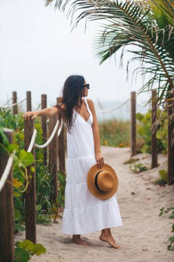 Yaz tatilinde plajda beyaz elbiseli genç bir kadın.