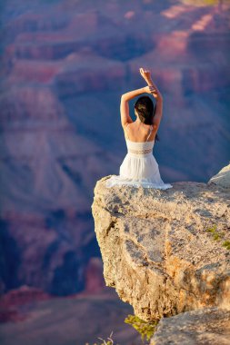 Dik bir uçurumda genç bir kadın, Arizona 'daki Grand Canyon Ulusal Parkı' nda gün batımında ünlü Büyük Kanyon 'un muhteşem manzarasını seyrediyor. Yüksek kalite fotoğraf