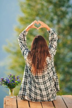 Genç bir kadının arka manzarası dağlarda bir terasta sislerin ve dağların ardında oturur.