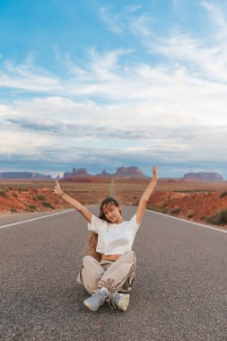 Happy girl raised her hands on the famous road to Monument Valley in Utah. Amazing view of the Monument valley. clipart