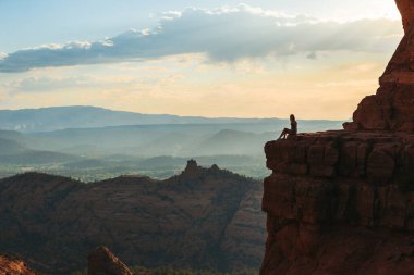 Sedona, Arizona 'da gün batımında Katedral Rock' ın kenarında genç bir kadın. Arizona 'da mavi gökyüzü olan Sedona' daki Scenic Cathedral Rock 'tan görüntü