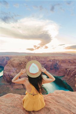 Arizona, Paje 'deki Horseshoe Kanyonu' nda uçurumun kenarında sarı elbiseli genç bir kız. Macera ve turizm konsepti. 