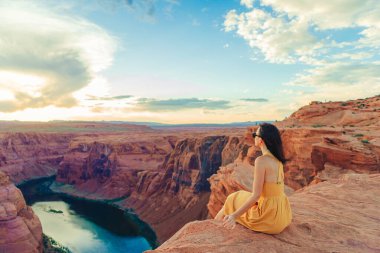 Arizona, Paje 'deki Horseshoe Kanyonu' nda uçurumun kenarında sarı elbiseli genç bir kız. Macera ve turizm konsepti. 