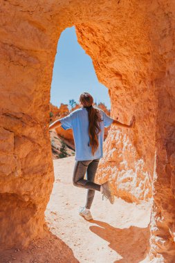 Bryce Canyon Ulusal Parkları, Utah, ABD 'de yürüyüş yapan mutlu genç kız. Genç kız kırmızı kumtaşından bir kemerin üzerinde duruyor.