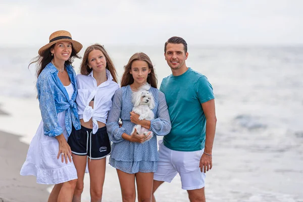 Portrait of two parents and two adorable teen daughters walking together on the beach vacation