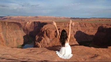 Uçurumun kenarında beyaz elbiseli genç bir kız. At nalı bandı kanyonu. Macera ve turizm konsepti. Yüksek kalite fotoğraf