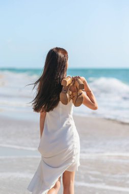 Genç ve güzel bir kadın tropik deniz kıyısında eğleniyor. Mutlu kız arka planda mavi gökyüzü ve denizdeki turkuaz su. Yüksek kalite fotoğraf