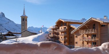 Fransa 'nın Tignes köyündeki kilise ve ahşap evler. Kışın açık mavi gökyüzü. Turizm, kayak, oteller, kayak yarışı.