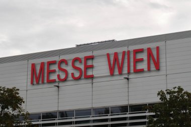 Sergi Kongre Merkezi binasının dışındaki Messe Wien logosu bulutlu bir günde. Viyana, Avusturya - 25 Eylül 2023.