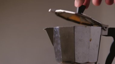 Sıcak kahve kaynıyor ve moka demliğinden buhar çıkıyor, yakın plan. Gri arkaplanda kahve makinesinde kaynamış kahve. Bir çaydanlıkla nefis kahve yapmak..