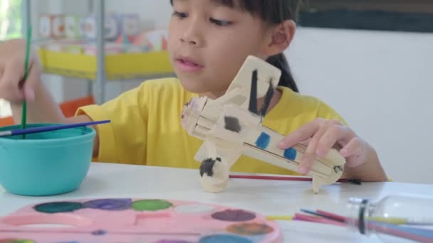 Portrait Happy Asian Girl Brush Painting Wooden Toy Plane Classroom — Stock Video