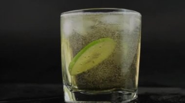 Siyah arka planda limonlu ve tuzlu altın Meksika tekilası. Limon dilimleri ve su sıçratma ile bir bardak tekila. Alkolik içki konsepti. seçici odak.