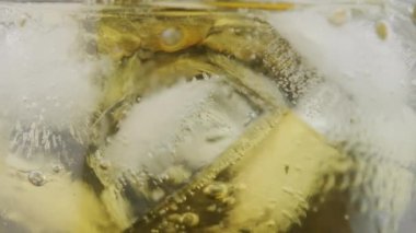 Yakın plan buzlu bardağa viski dökerken. Alkolik içki konsepti. seçici odak.