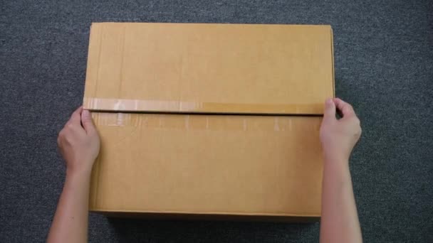 製品で段ボール箱を開ける手のクローズアップ 女性の顧客の手は良い小包を受け取り 箱を開梱しました 郵便配達の概念を注文 — ストック動画
