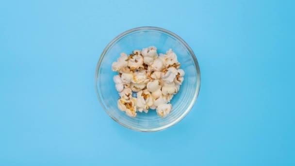 在淡蓝色背景的玻璃碗里停止美味爆米花的运动 电影小吃和娱乐概念 — 图库视频影像