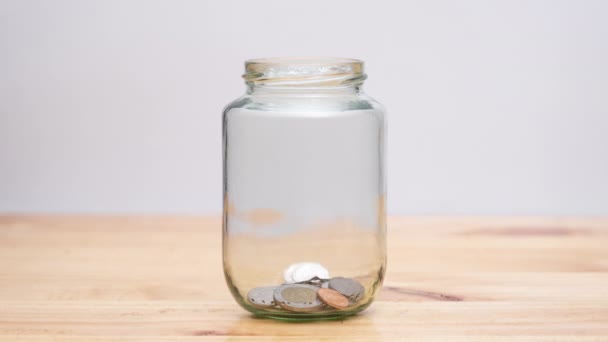停止在木制桌子上的透明玻璃瓶中移动硬币动画 储蓄增长货币概念 — 图库视频影像
