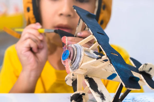 教室の木製のおもちゃの飛行機にブラシの絵と幸せなアジアの女の子の肖像画 子供のための芸術品や工芸品 創作活動中の小さなアーティスト — ストック写真