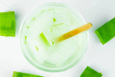 Cam kasede taze aloe vera suyu ve beyaz arka planda doğal organik aloe vera dilimleri. tıp ve güzellik konsepti.