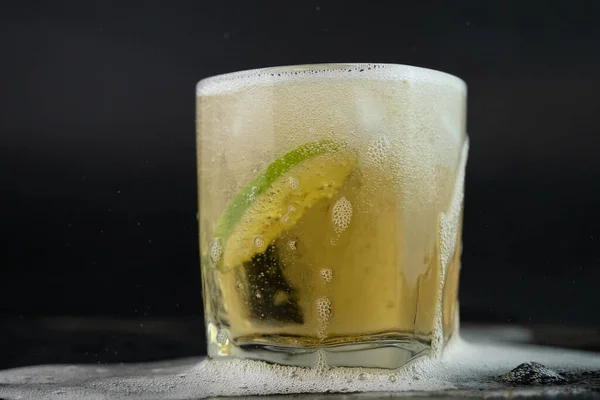 用金黄色墨西哥龙舌兰加石灰和盐在黑色背景上拍摄 一杯龙舌兰酒加柠檬片和水花酒精饮料的概念 选择性重点 — 图库照片
