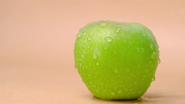 Zeitlupe Spritzt Wasser Auf Frischem Grünen Apfel Auf Beigem Hintergrund — Stockvideo