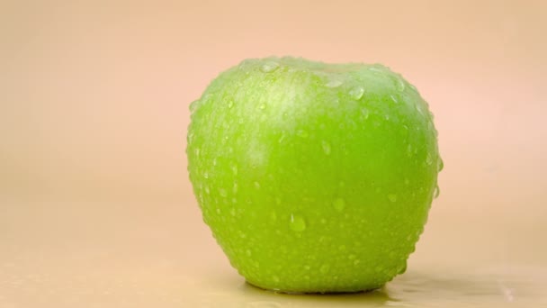 Zeitlupe Spritzt Wasser Auf Frischem Grünen Apfel Auf Beigem Hintergrund — Stockvideo