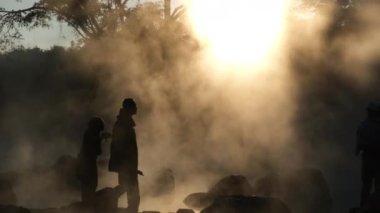 January 8, 2023; Hot springs and fog in Thailand with morning sunlight. Morning atmosphere at Chae Son National Park, silhouettes of tourists enjoying the beauty of hot springs in Lampang, Thailand.