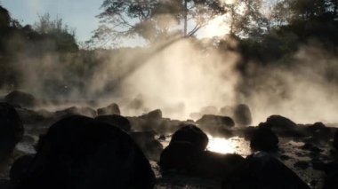 January 8, 2023; Hot springs and fog in Thailand with morning sunlight. Morning atmosphere at Chae Son National Park, silhouettes of tourists enjoying the beauty of hot springs in Lampang, Thailand.